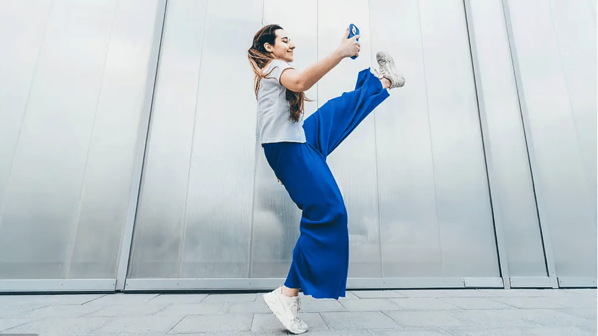 Woman stretching outdoors against a light-colored wall