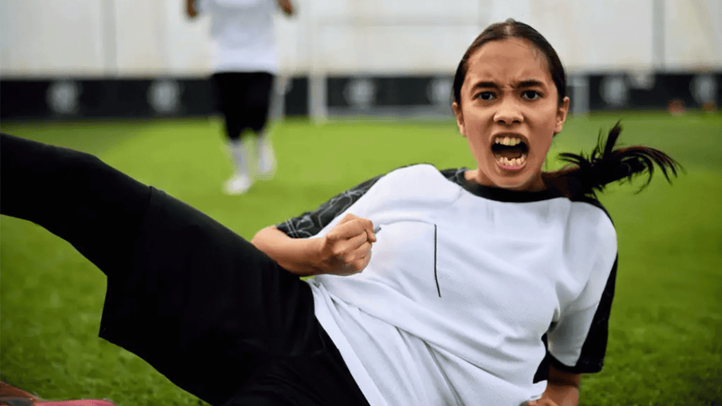 Person in sports uniform kicking on a grass field